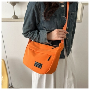Modella che indossa borsa a tracolla arancione in nylon con giacca di jeans e gonna