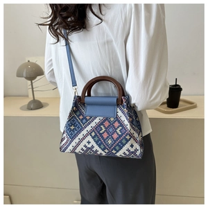 Close-up of bohemian woven handbag with geometric patterns and round wooden handle