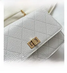 Close-up of beige quilted leather shoulder bag with golden twist lock and chain strap