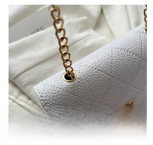 Detail view of gold eyelet and chain strap on white quilted crossbody bag texture