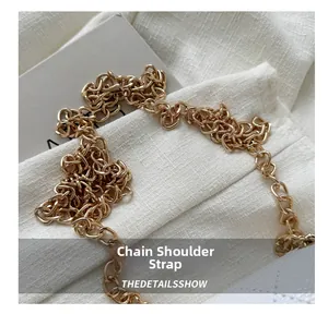Close-up of polished gold metal chain strap with classic interlocking rings for bags