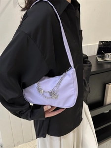 Minimalist lavender underarm bag with butterfly silver chain shown in a lifestyle setting