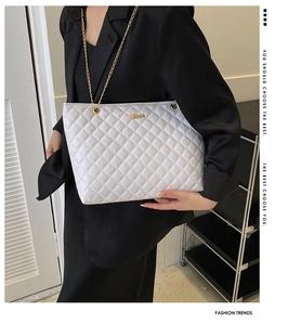 Macro detail of white quilted tote bag with gold chain strap and elegant hardware