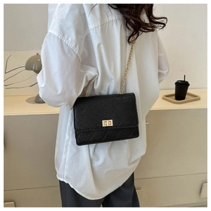 Detail of black quilted leather crossbody bag with gold twist lock and chain strap