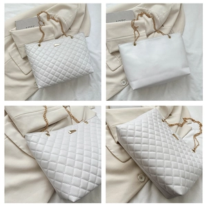 Detail view of white quilted tote bag featuring golden chain straps and metallic hardware