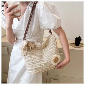 Détail du sac cabas en paille tissée avec nœud en dentelle et décor de marguerite