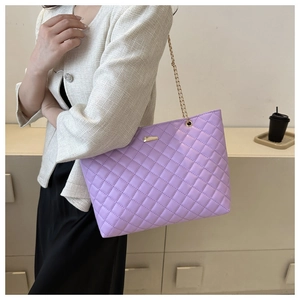 Detail view of purple quilted tote bag with gold chain strap and metal decoration