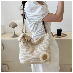 Détail du sac cabas en paille tressée crème avec un nœud en dentelle et décor de tournesol