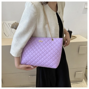 Close-up of a purple quilted leather chain bag worn by a model in an elegant indoor setting
