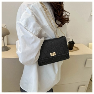 Close-up of quilted black leather crossbody bag with golden chain and twist lock