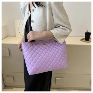 Detail of lilac quilted shoulder bag with gold chain strap and metallic brand plate