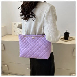 Detail of purple quilted shoulder bag with gold chain strap and metallic lock clasp