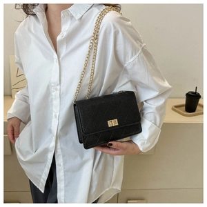 Close-up of a black quilted leather crossbody bag featuring gold chain and turn-lock