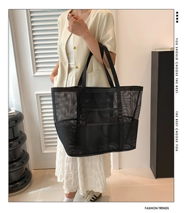 Large capacity black mesh beach tote bag with wide nylon handles carried by a model