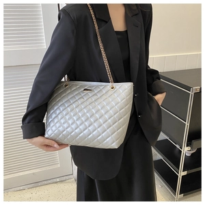 Detail of silver quilted tote bag with gold chain strap and metallic finish on model