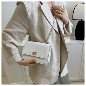 Close-up of white quilted leather crossbody bag with gold chain strap and turn-lock closure