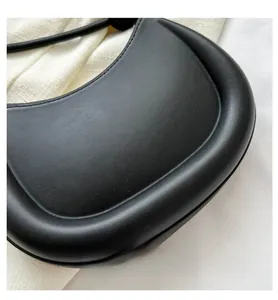 Detailed close-up of a black crescent shoulder bag featuring padded edges and premium texture