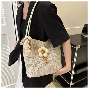Détail d'un sac cabas tissé beige avec fleurs en tissu et ruban en dentelle