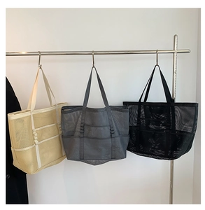 Close-up of mesh beach bags with front pockets in beige, dark grey, and black colors