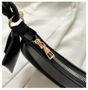 Close-up of golden metal zipper and D-ring attachment on high-quality black leather bag
