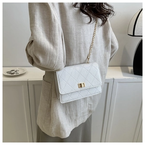 Detailed view of white quilted crossbody bag with gold chain strap and twist lock on a model