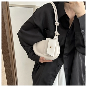 Mirror selfie showing a cream saddle bag with a mini pouch and knotted shoulder strap