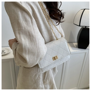 Detail of white quilted crossbody bag featuring a gold twist lock and chain strap