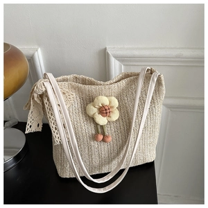 Détail d'un sac cabas en paille beige avec fleur tricotée 3D et bordure en dentelle
