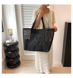 Detail of a large black mesh beach tote bag featuring breathable nylon fabric and handles