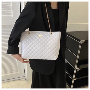 Detail shot of white quilted shoulder bag featuring gold chain and metallic buckle