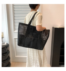 Detailed view of black mesh beach bag with functional exterior pockets on model