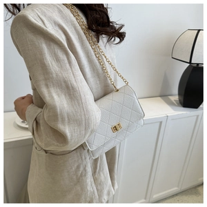 Macro shot of white quilted leather bag with gold chain strap and elegant twist lock