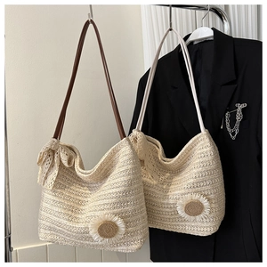 Détail du sac cabas en paille avec fleur 3D et nœud en dentelle sur blazer noir