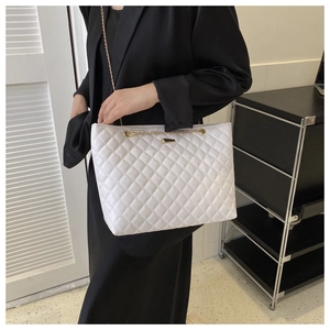 Close-up of white quilted tote bag with diamond pattern and gold chain strap detail