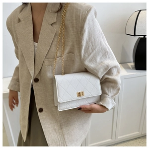 Close-up of a white quilted crossbody bag with a gold metal clasp and chain strap