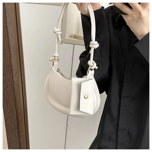 Close-up of cream hobo bag with unique knotted strap and matching side pouch detail