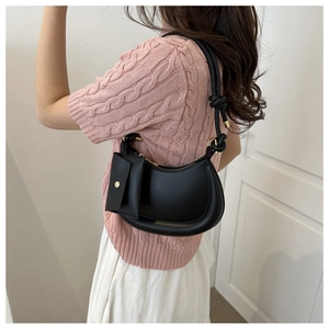 Detailed view of a black crescent shoulder bag with a small pouch on a stylish model