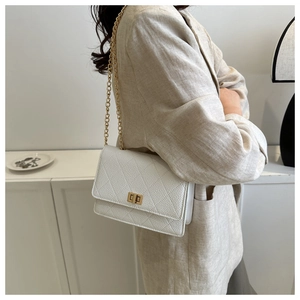 Close-up of white quilted leather cross-body bag with golden twist lock and chain strap