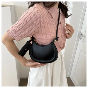 Side view of black crescent shoulder bag with small coin purse on a fashion model