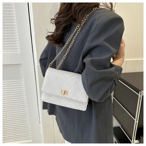 Detail of white quilted crossbody bag with golden chain and metal twist lock on a model