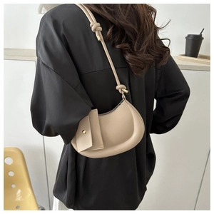 Detail of beige crescent shoulder bag with knot strap and detachable small pouch