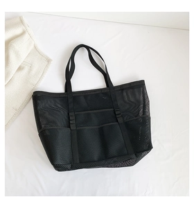 Close-up of black mesh beach tote bag featuring three front pockets and reinforced handles