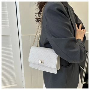 Detail of white quilted crossbody bag with golden chain and square twist lock