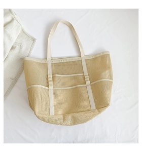 Detail view of large beige mesh beach tote bag with reinforced handles and multi-pocket storage
