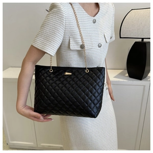 Detail of black quilted leather texture and gold chain strap on women bucket bag