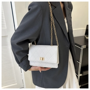 Close-up of white quilted leather bag with gold chain strap and metal swivel lock on model