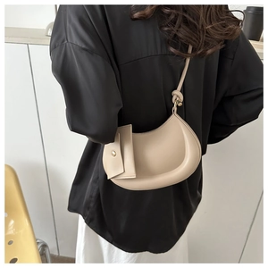 Detail of beige half-moon crossbody bag with knot shoulder strap and small pouch