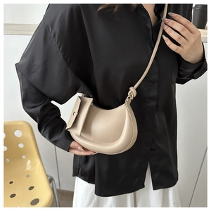 Detail of beige crossbody bag with cashew shape and mini coin purse on knotted strap