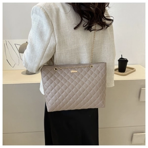 Detail of quilted stitching and gold chain strap on a stylish gray-brown tote bag