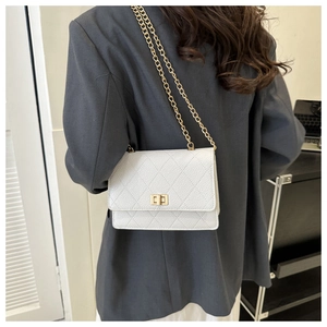 Detail of white quilted leather bag with gold chain strap and metallic twist lock closure